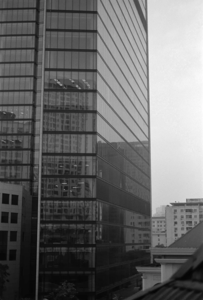 A glass office tower reflects a second building in a grid of grey windows