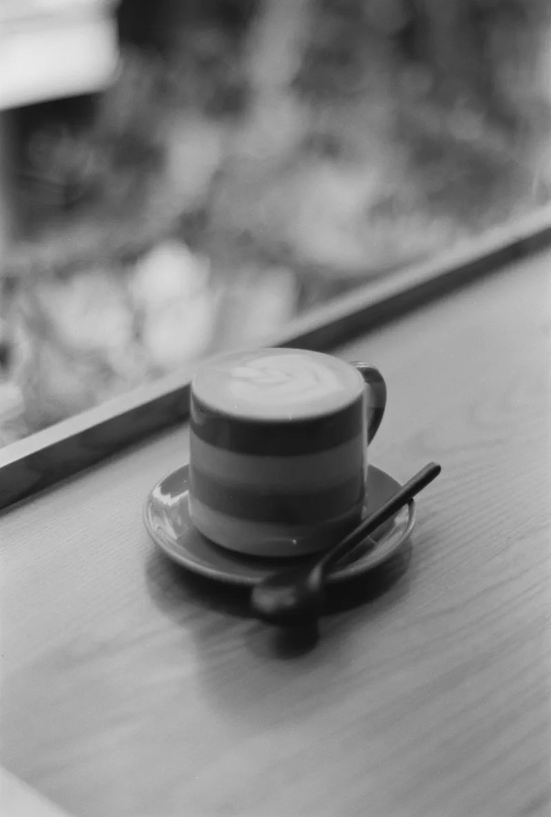 A striped ceramic cup and spoon sit beside a window softened by condensation