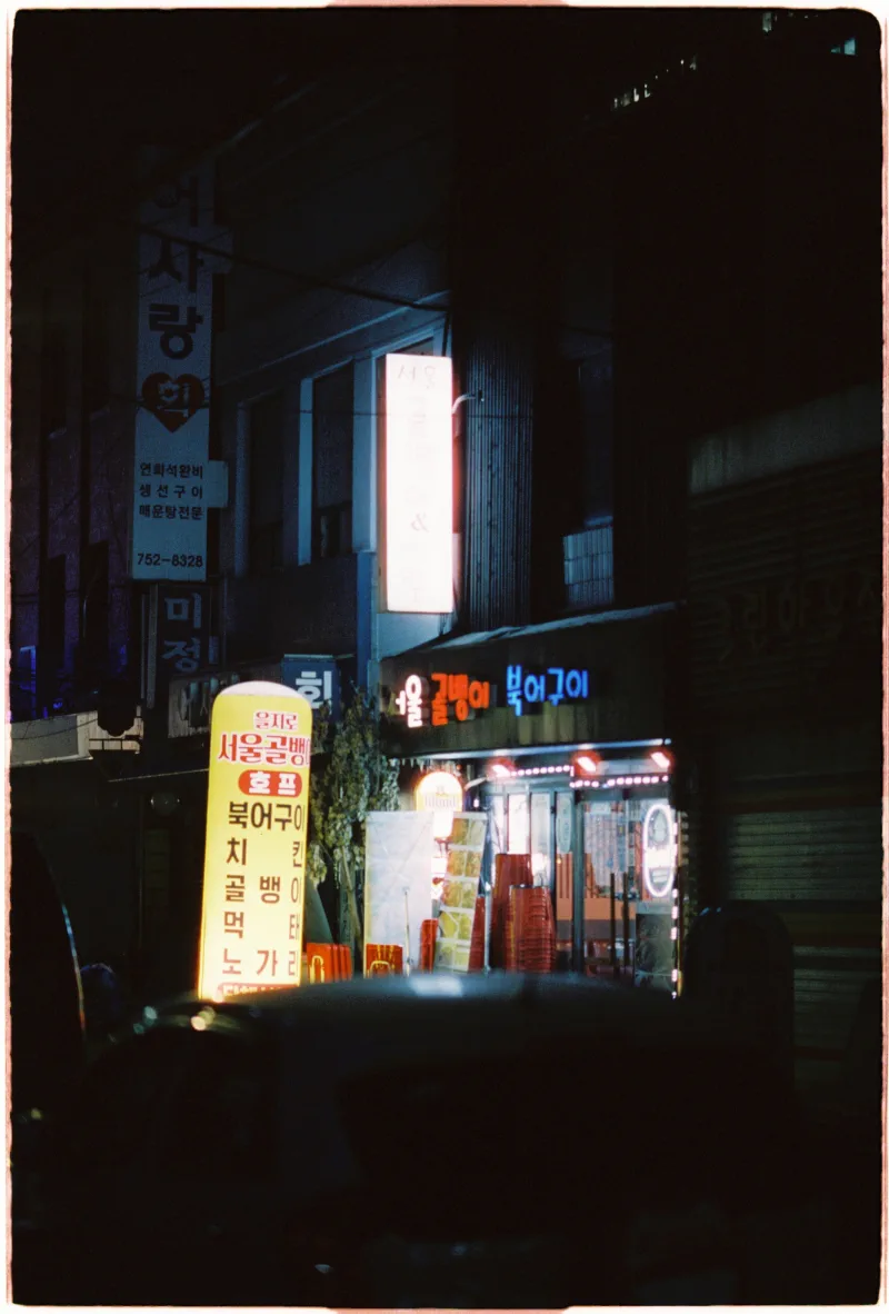 An empty Seoul side street framed by Korean restaurant signs and blue-red neon